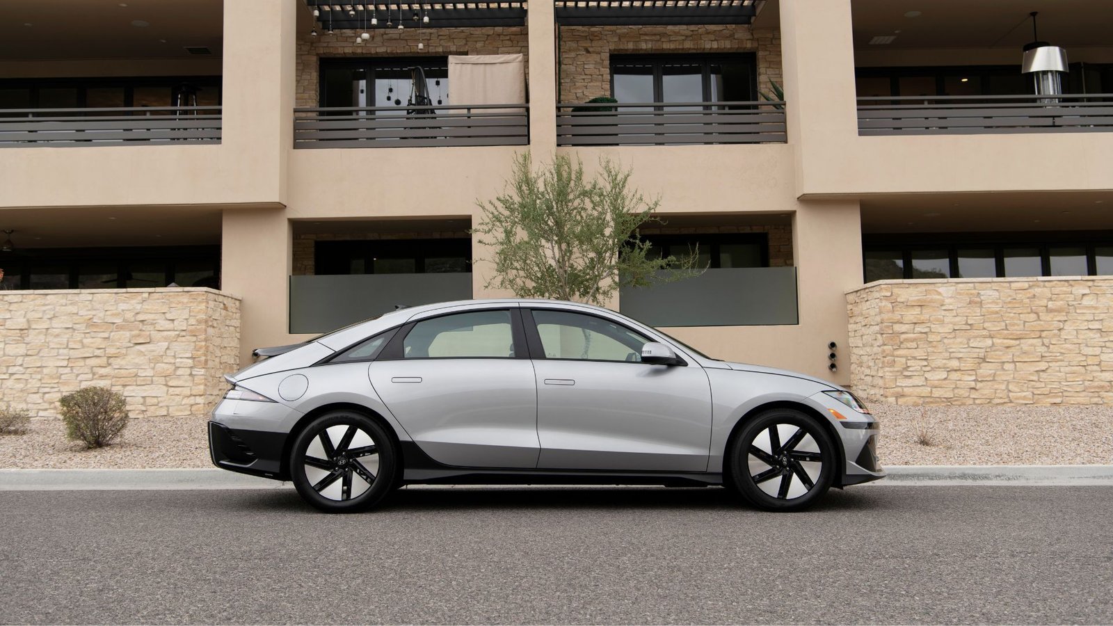 Profil latéral statique Dot de Silver 2025 Hyundai Ioniq 6 SE stationné à l'extérieur d'un immeuble résidentiel.
