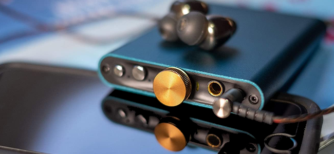 Un DAC portable Aqua Marine reposant sur un smartphone.