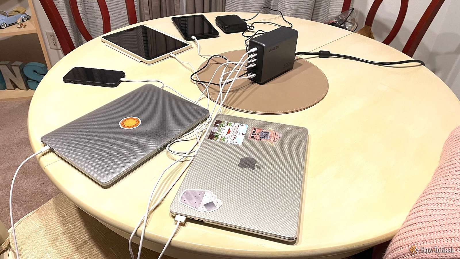 Le chargeur de bureau Ugreen Nexode 500W connecté à deux MacBooks, un iPhone, un iPad, un Kindle et un chargeur portable.