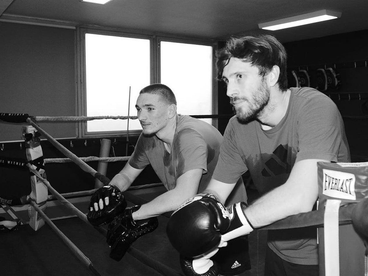 Deux hommes portant des gants de boxe se penchant sur l'anneau