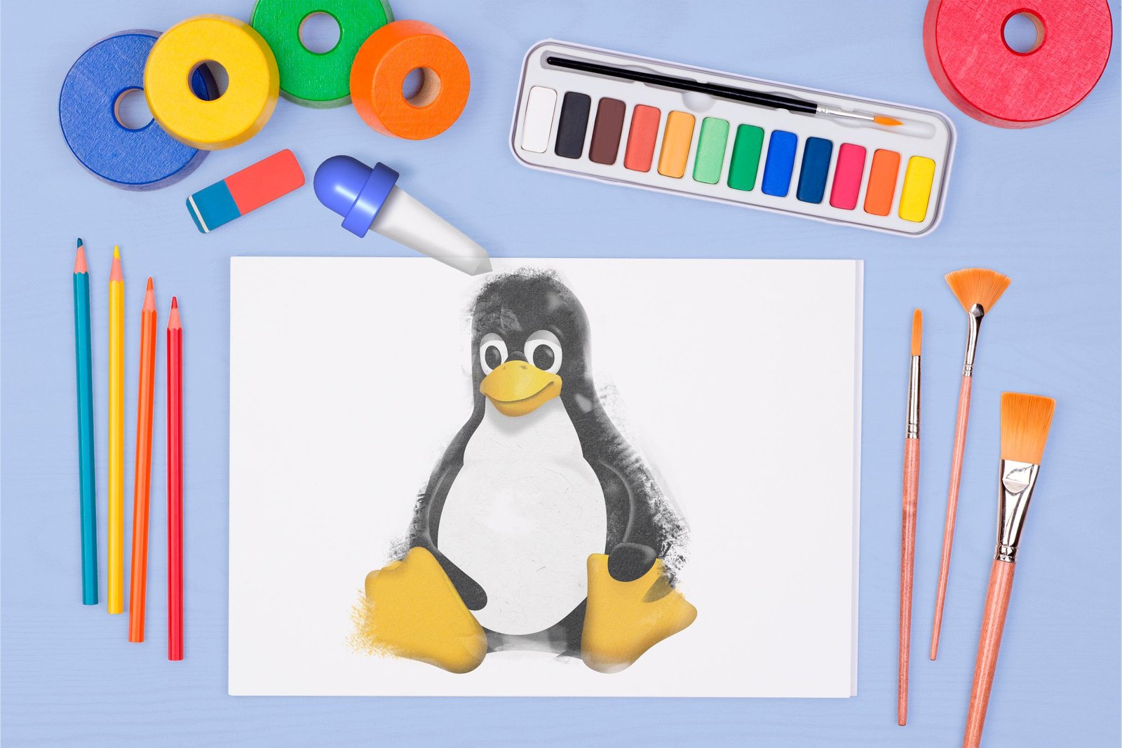 Une feuille de papier avec la mascotte Linux et des éléments de dessin et de peinture autour de lui.