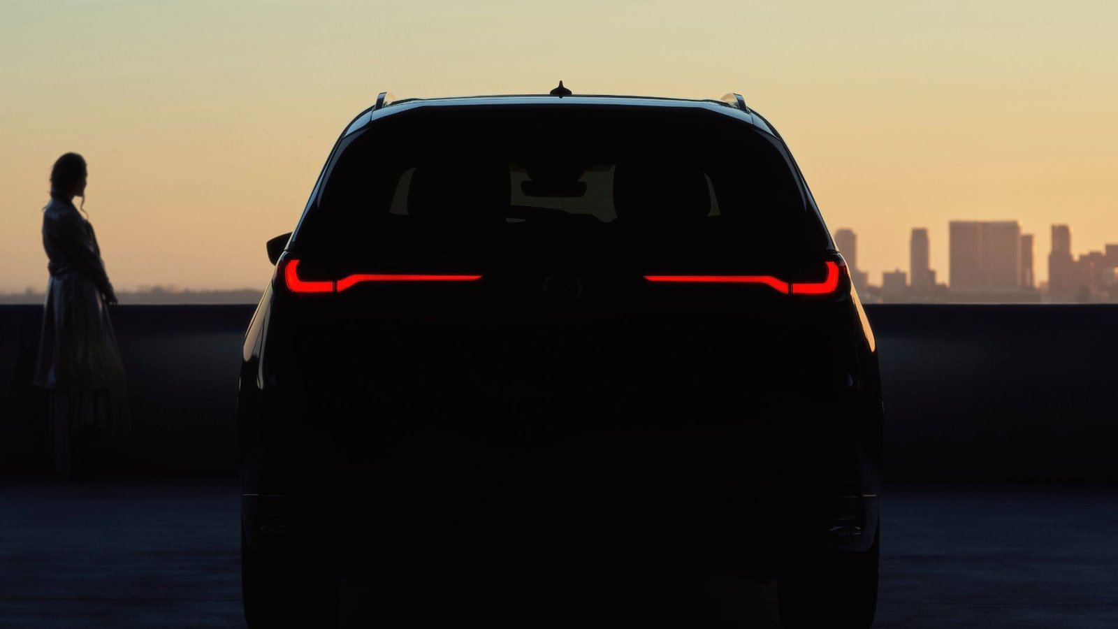 THE STATIQUE DE L'ARRIEUX D'UNE UNE MAZDA CX-90 2025 GADÉS DANS L'HAMPRE avec un paysage urbain en arrière-plan.