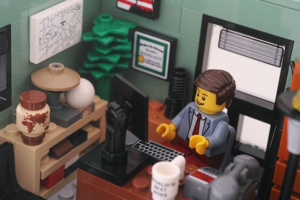 Un minifigure d'homme d'affaires LEGO assis et travaillant derrière un ordinateur dans un bureau.