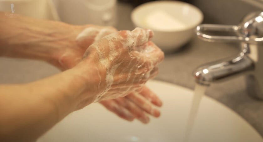 Personne se lavant les mains avec du savon dans un évier, renforçant l'hygiène et l'étiquette respectueuse des toilettes.