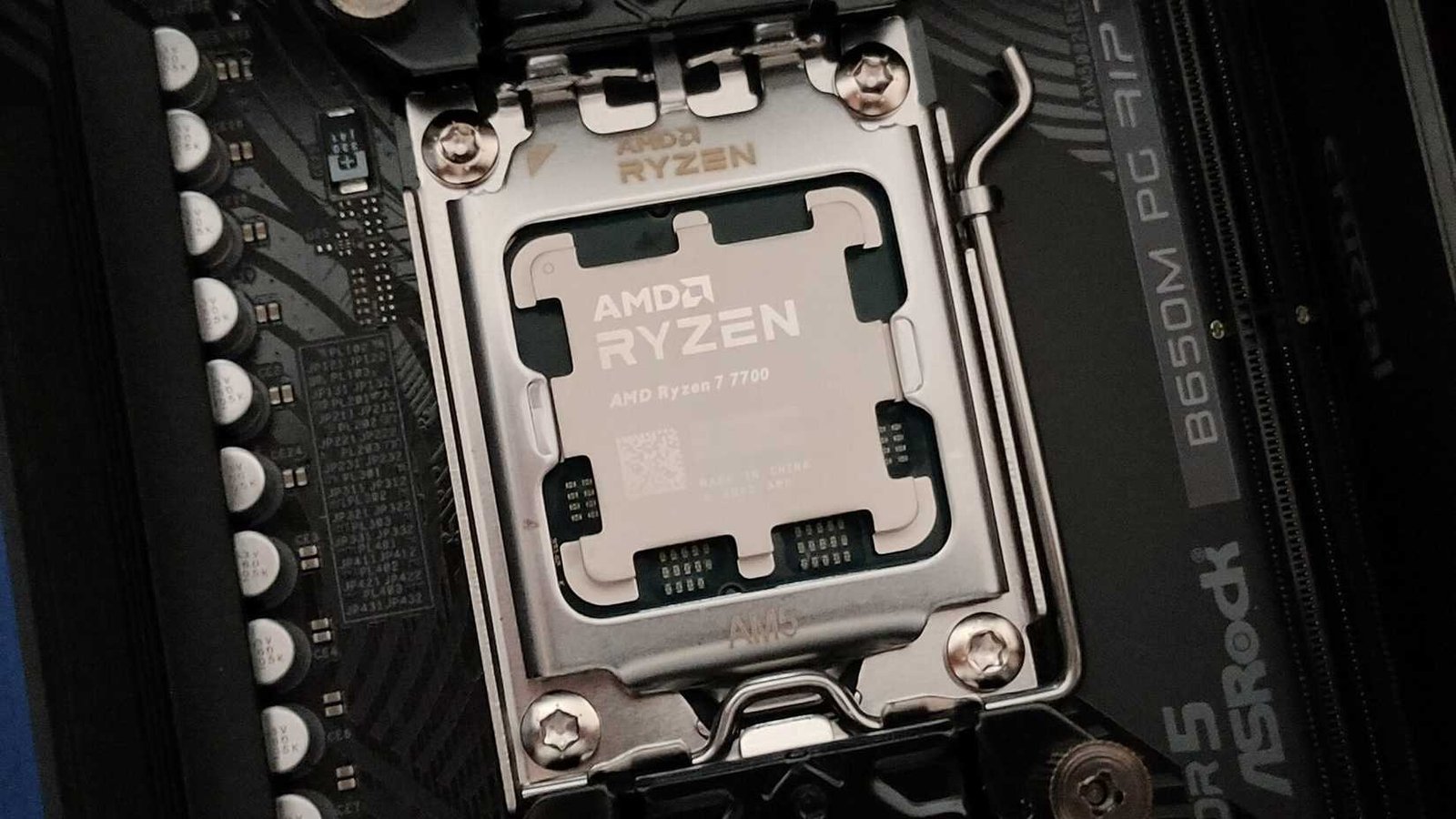 Une photo rapprochée du processeur AMD Ryzen 7 7700 dans la douille AM5 et la carte mère ASROCK B650M PG Riptide.