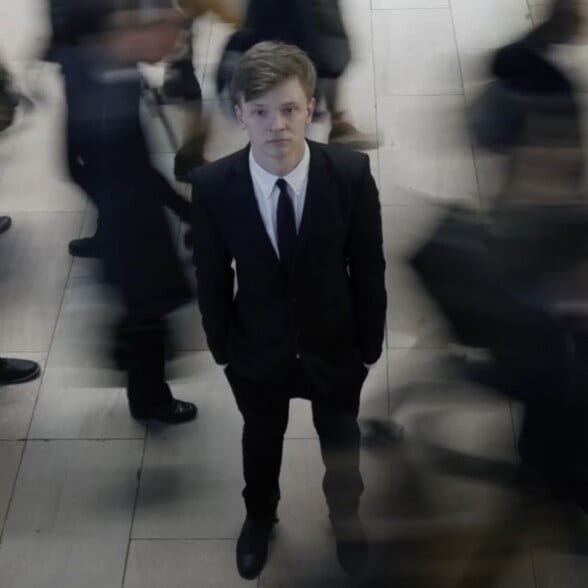 Ressentiment envers l'histoire formelle de la robe Jeune homme en costume debout parmi une foule floue