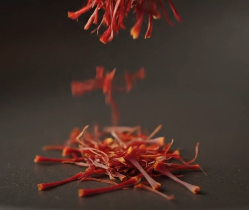 Cuisine à épices aux brins de safran brins de safran tombant sur une surface sombre
