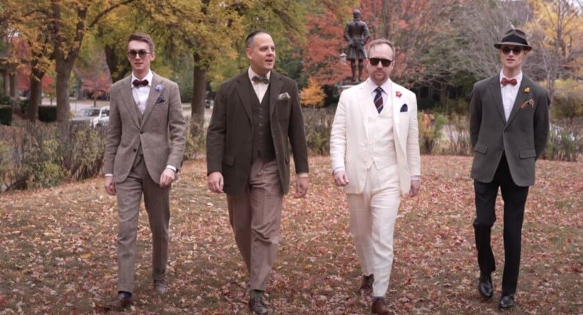 Quatre hommes en costumes sur mesure marchant ensemble à Autumn Park