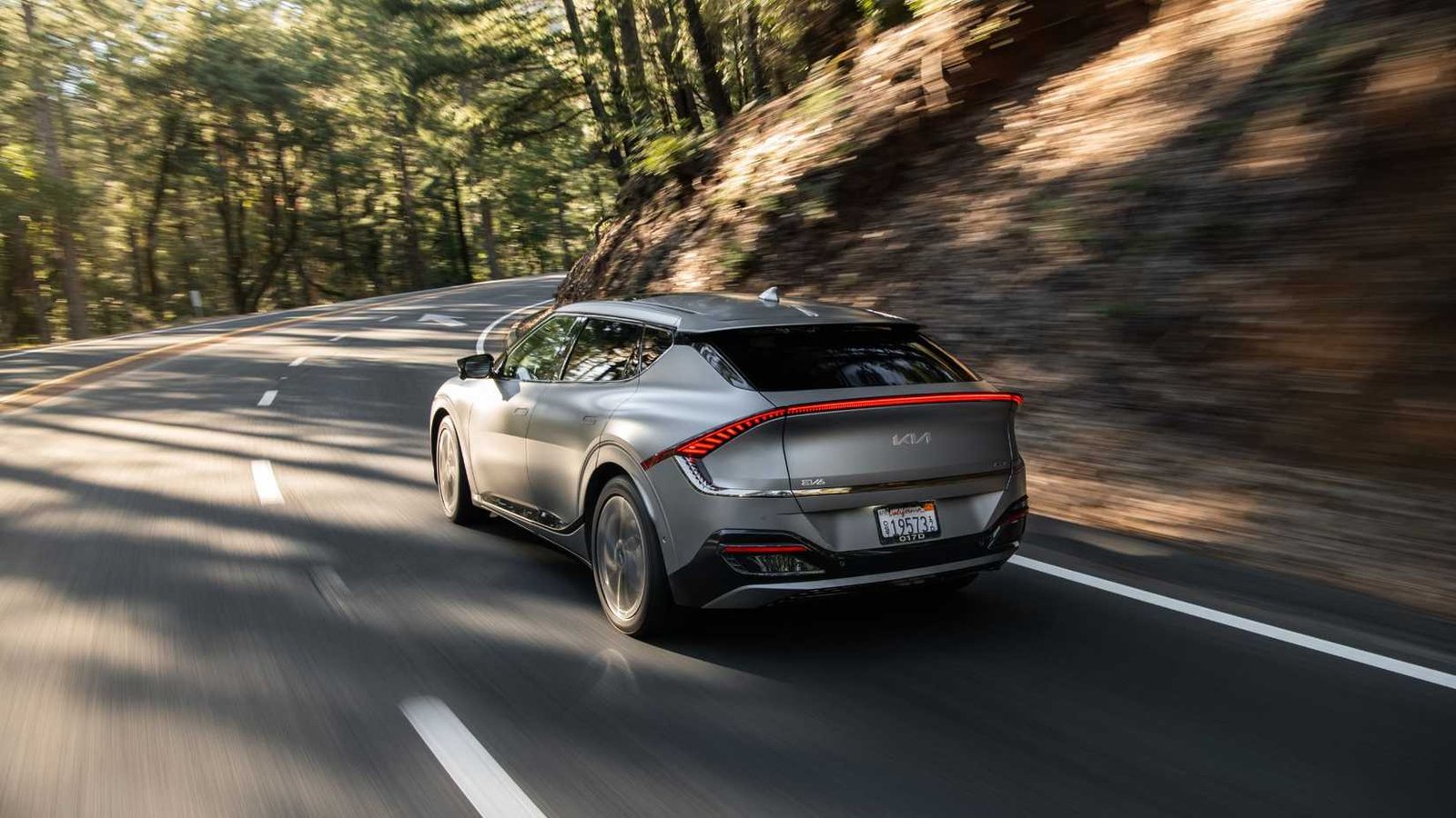 Dynamic arrière 3/4 tir d'un Kia EV6 gris 2022 conduisant sur une route country sinueuse.