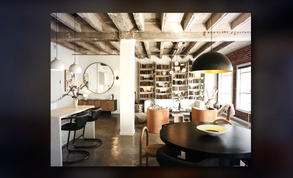 Bibliothèque de plafond exposée grenier industriel Espace de vie de grenier industriel avec poutres exposées, miroir rond et bibliothèque intégrée.