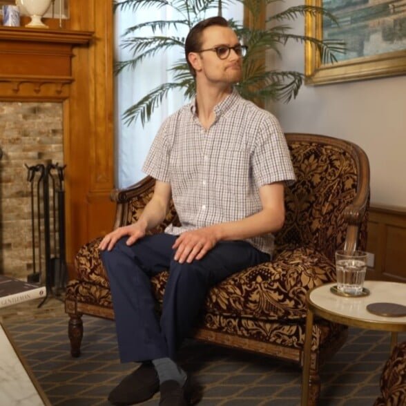 Assis les chevilles croisées Homme assis avec des jambes croisées aux chevilles sur un fauteuil