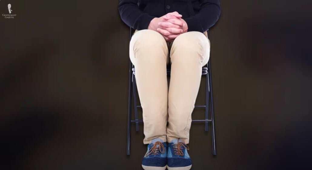 Les jambes assises ensemble à 90 degrés Homme assis avec les genoux ensemble et les pieds à plat à un angle à 90 degrés