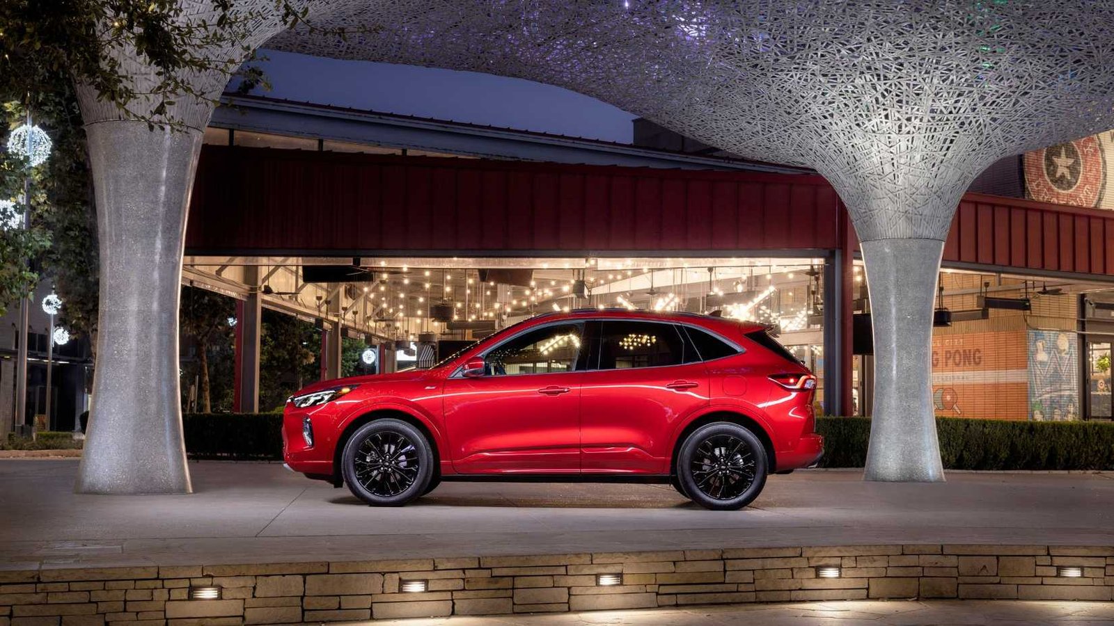 Profil latéral statique Dot d'une élite rouge 2023 Ford Escape grée à l'extérieur d'un bâtiment moderne.