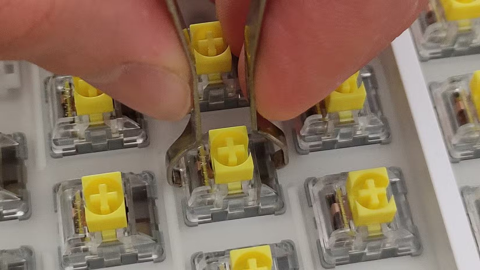 Un gros plan d'une main en supprimant un interrupteur de clavier mécanique à l'aide d'un tireur d'interrupteur.