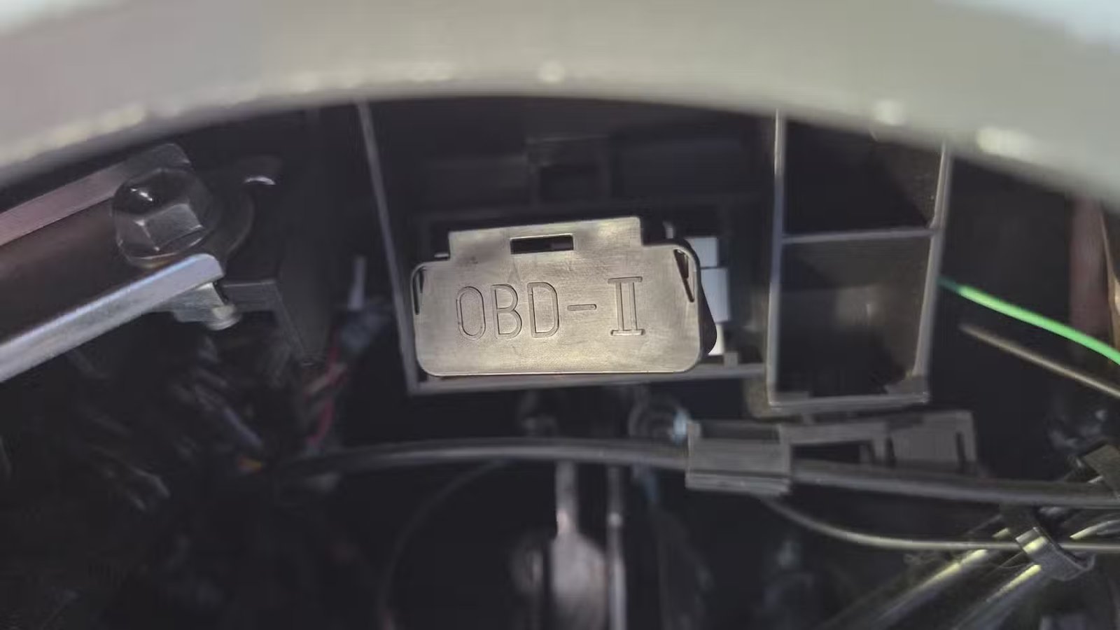 Port OBD-II à l’intérieur d’une voiture avec le couvercle en place. 