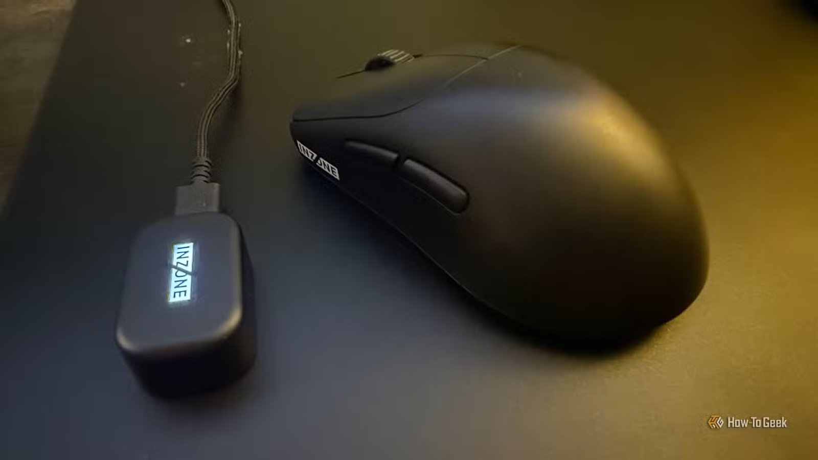 Le Sony Inzone Mouse-A et son dongle sans fil illuminé sur une souris en verre.