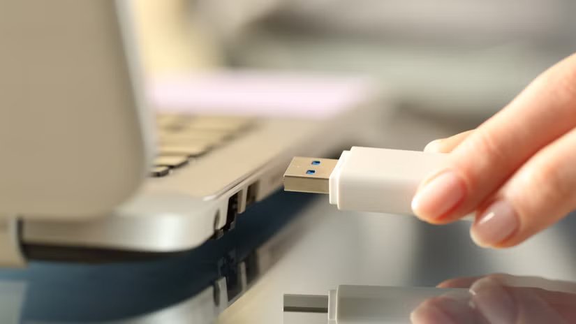 Gros plan de la main d'une femme branchant une clé USB sur un ordinateur portable.