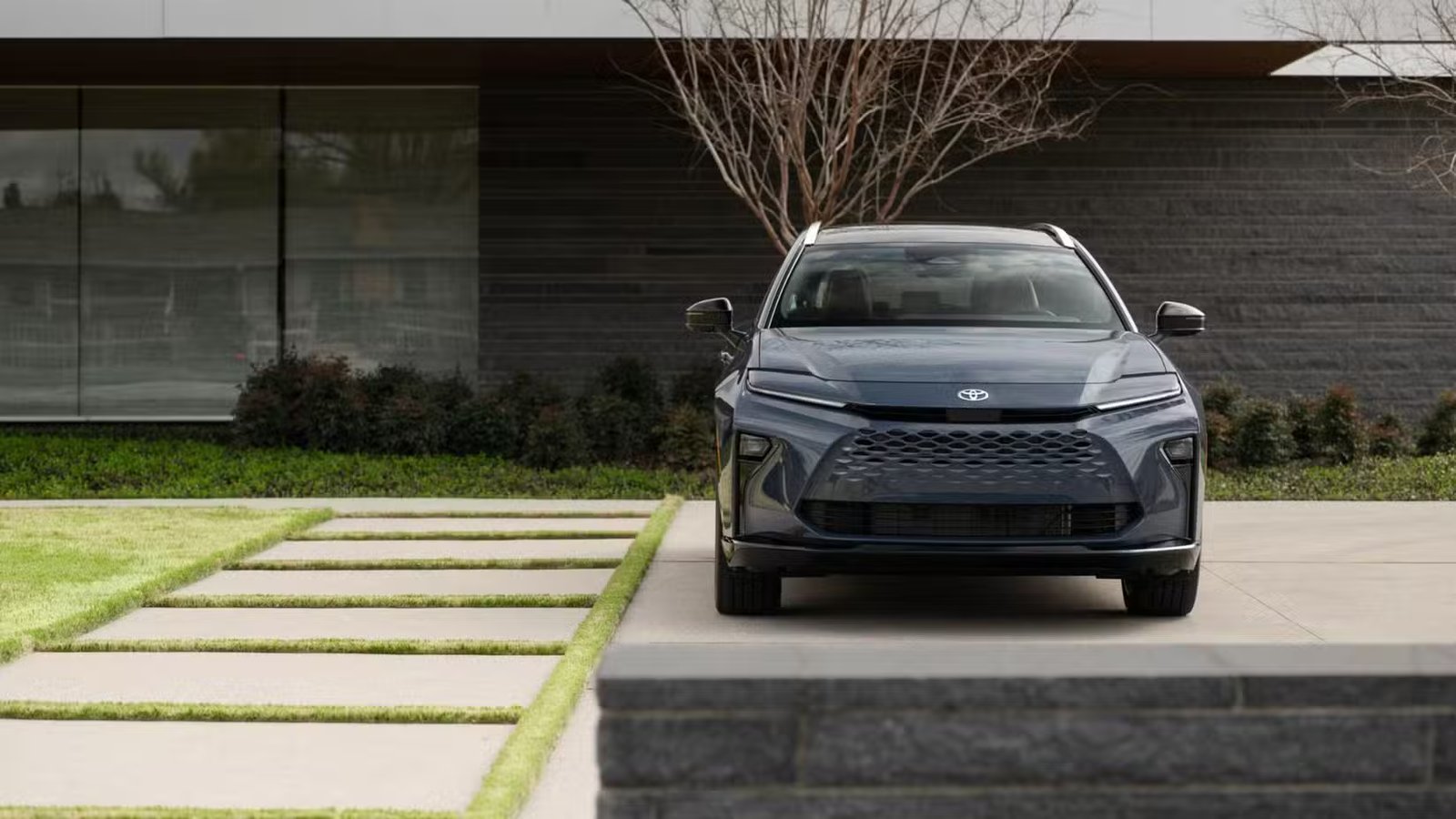Photo statique de l'avant d'une Toyota Crown Signia Limited 2025 grise garée à l'extérieur d'un bâtiment moderne.