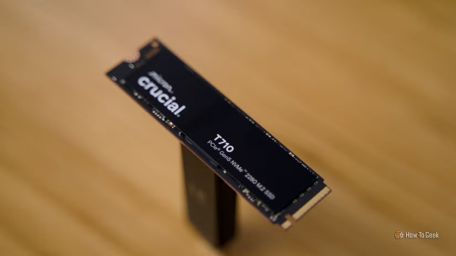 Le SSD Crucial T710 NVMe est posé sur un bureau en bambou.