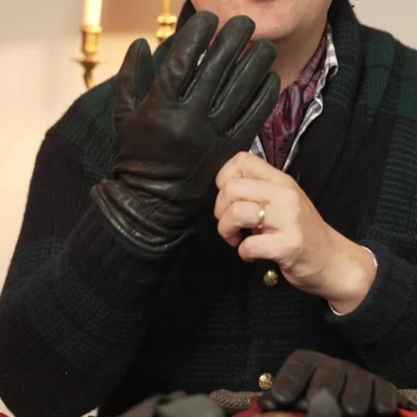 Raphael Schneider porte une paire de gants en cuir noir décevants et volumineux qui s'étirent avec le temps.