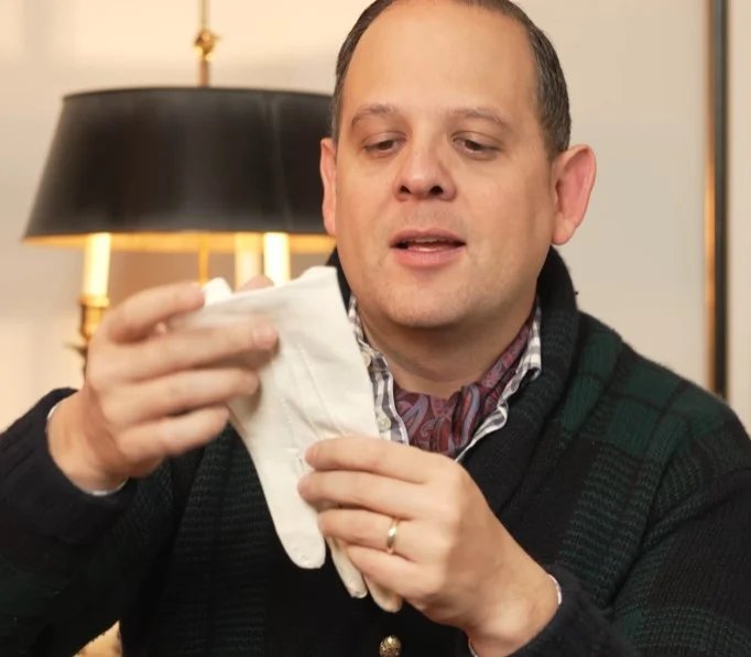 Raphael Schneider tenant une paire de gants en nappa d'agneau blanc adaptés aux tenues de soirée.