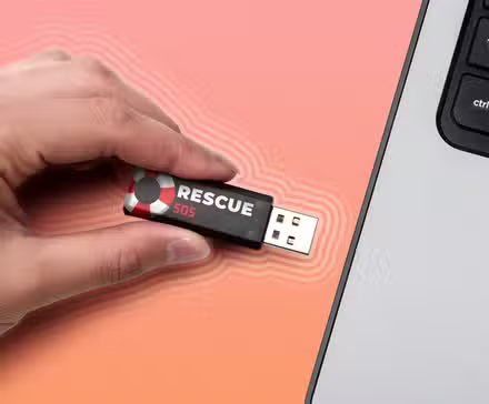 Insertion manuelle d'une clé USB intitulée « Rescue SOS » dans un ordinateur portable.
