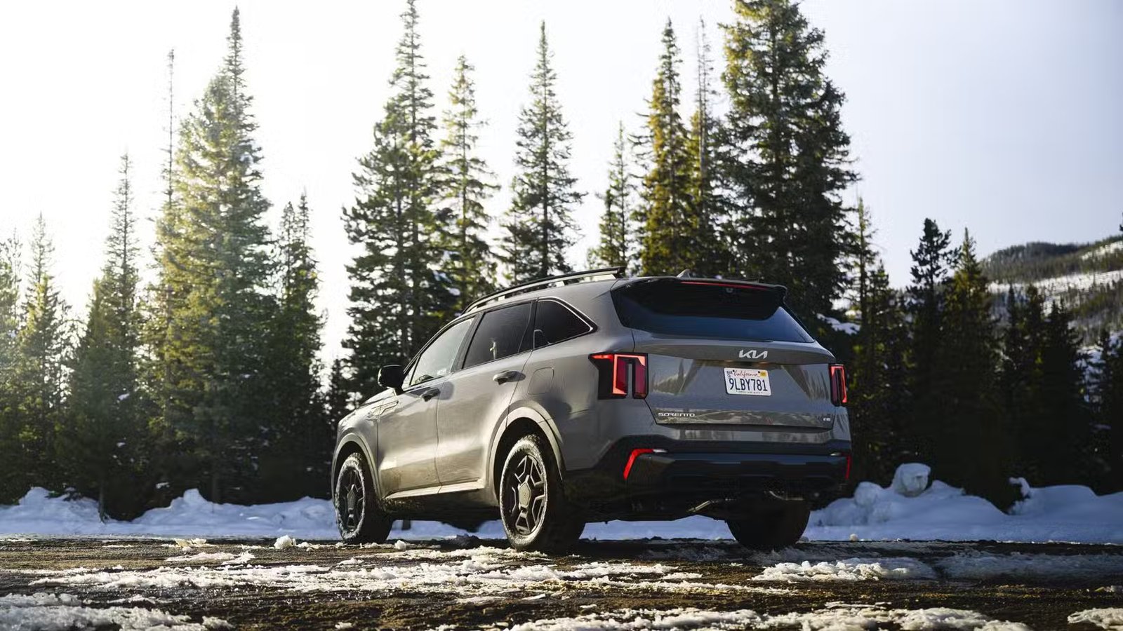 Plan statique 3/4 arrière d'un Kia Sorento 2026 garé dans la neige avec des arbres en arrière-plan.