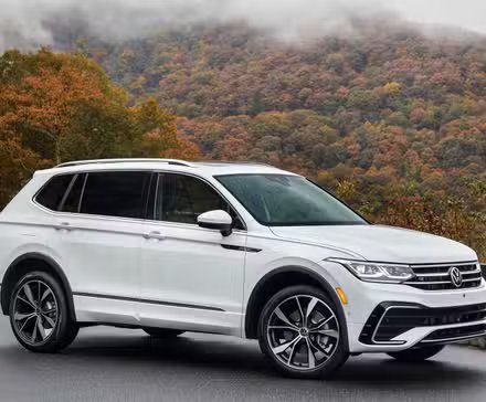 Vue de trois quarts avant d'un Volkswagen Tiguan 2024 blanc garé sur le bord de la route dans les montagnes.