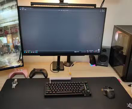 Un bureau d'ordinateur propre avec un PC de jeu, un clavier mécanique, une souris, des contrôleurs et deux moniteurs.