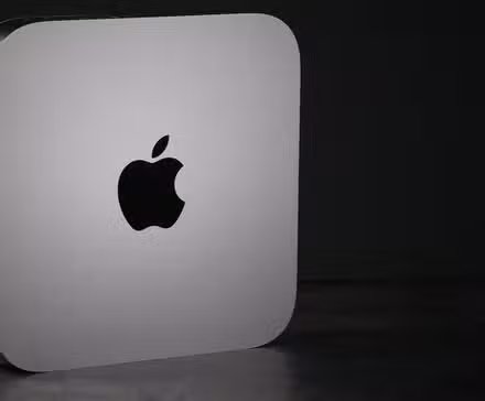 Un Mac Mini debout sur le côté sur un fond sombre.