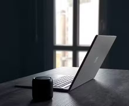 Un ordinateur portable Windows à côté d'un haut-parleur Bluetooth sur une table