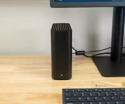 Le Synology BeeStation à côté d'un écran d'ordinateur.