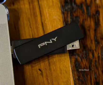 La clé USB PNY Duo Link V3 branchée sur un MacBook Pro posée sur une table en bois avec le côté USB-A dépassant légèrement.