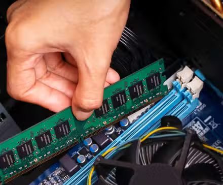Quelqu'un installe une barrette de RAM dans un ordinateur.