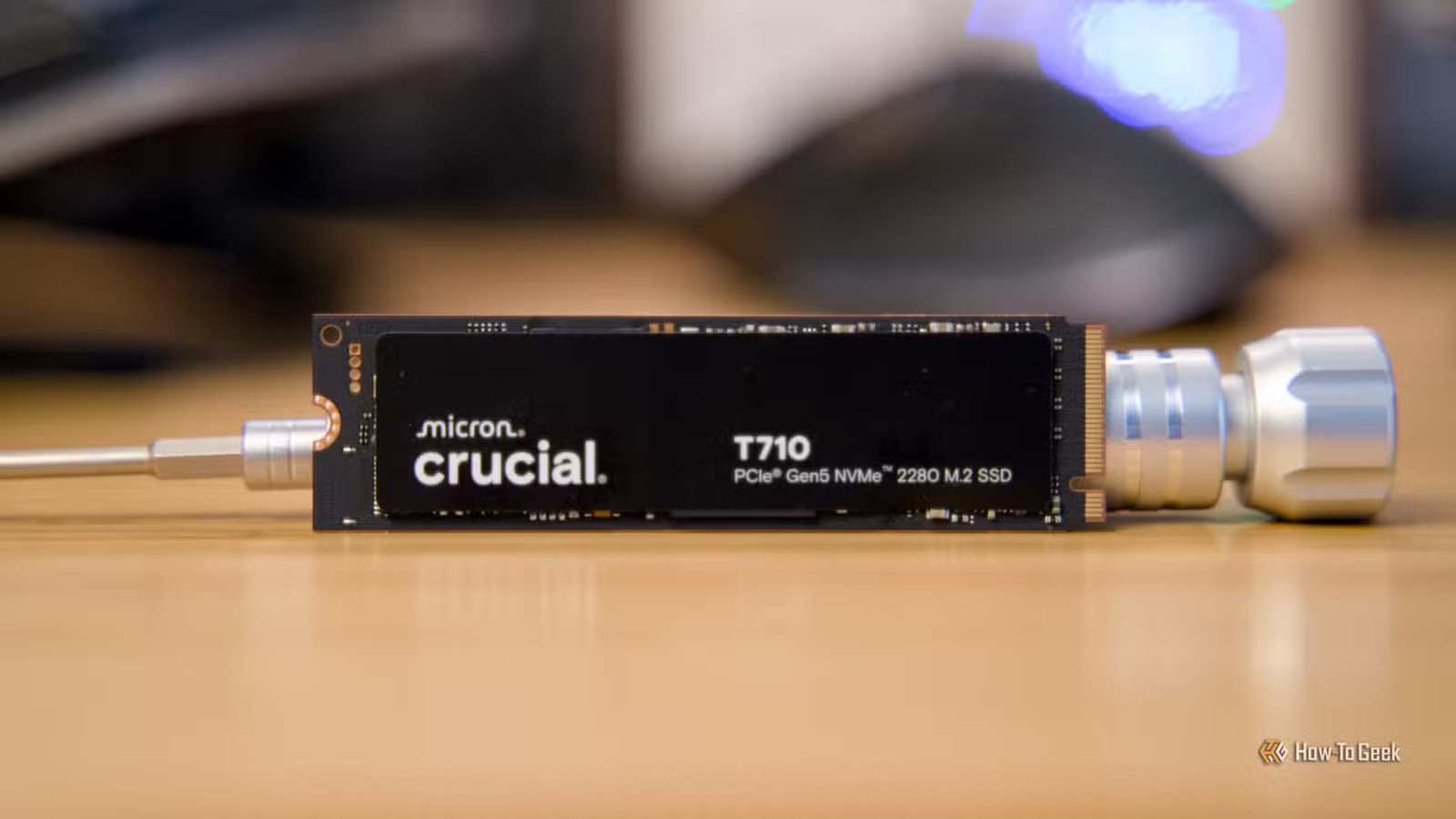 Le SSD Crucial T710 NVMe calé sur un bureau par un tournevis métallique.