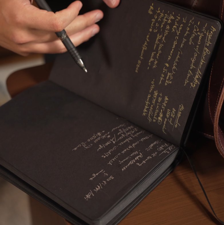 Ivan Noir Cahier Edc 2026 Gros plan des mains écrivant à l'encre blanche sur les pages noires