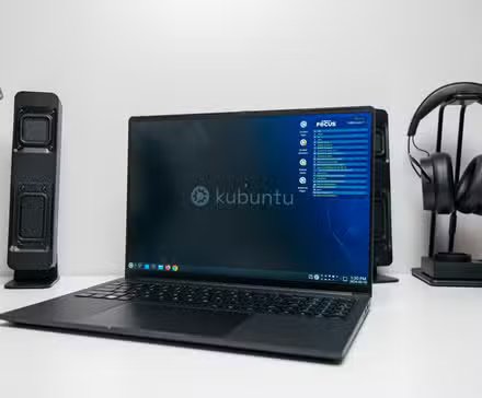 L'ordinateur portable Kubuntu Focus Ir16 Gen 2 ouvert sur un bureau devant des enceintes et un casque.