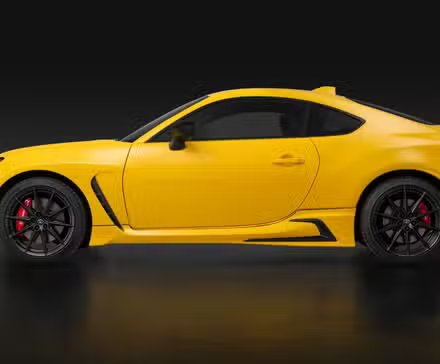 Photo de profil latéral d'une Toyota GR86 Yuzu 2026 jaune dans un studio sur fond noir.