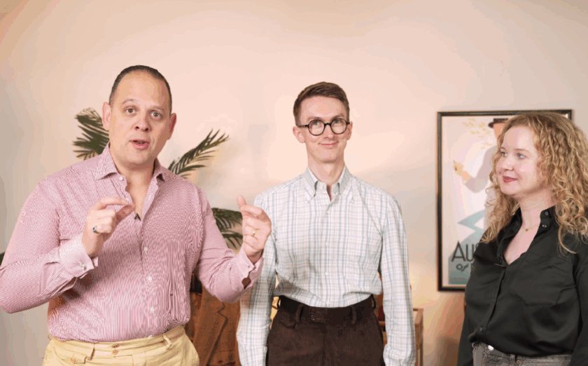 Sven Raphael Schneider (à gauche), Jack Collins (au centre) et Elin Estelle (à droite) discutent des pantalons pour hommes. Raphaël porte une chemise boutonnée rose et un pantalon jaune, Jack porte une chemise à carreaux blancs et un pantalon marron, et Elin porte une chemise en soie noire et un jean gris.