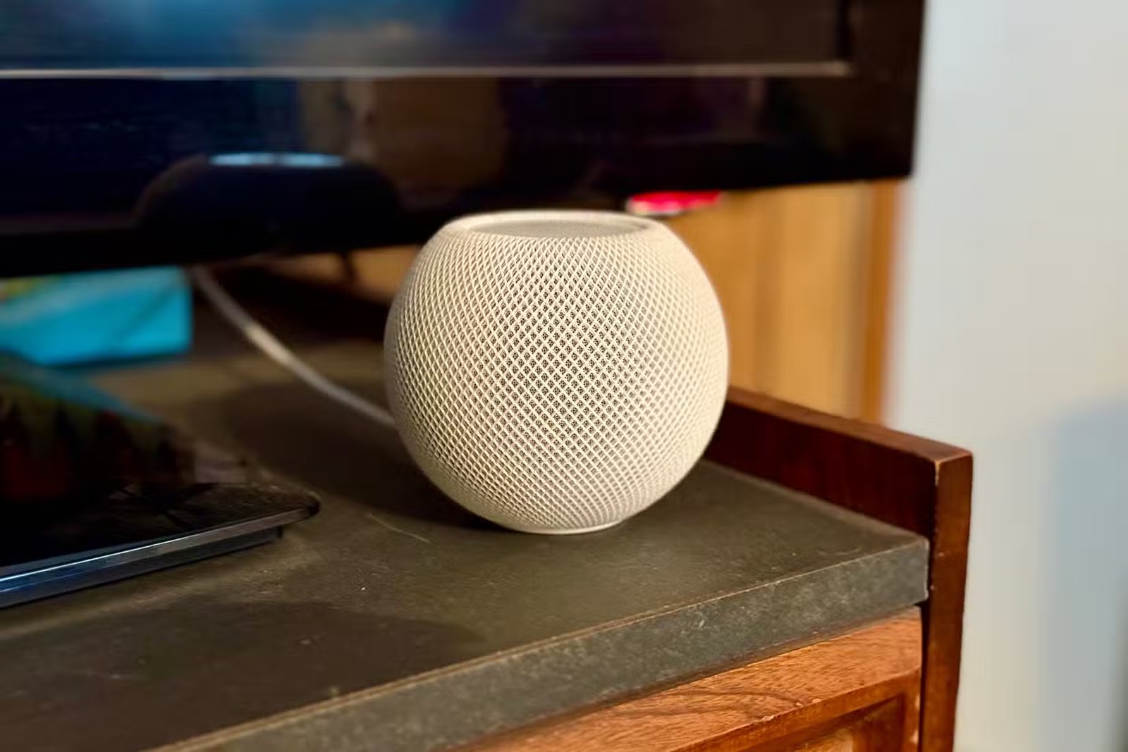 HomePod mini blanc devant un téléviseur.