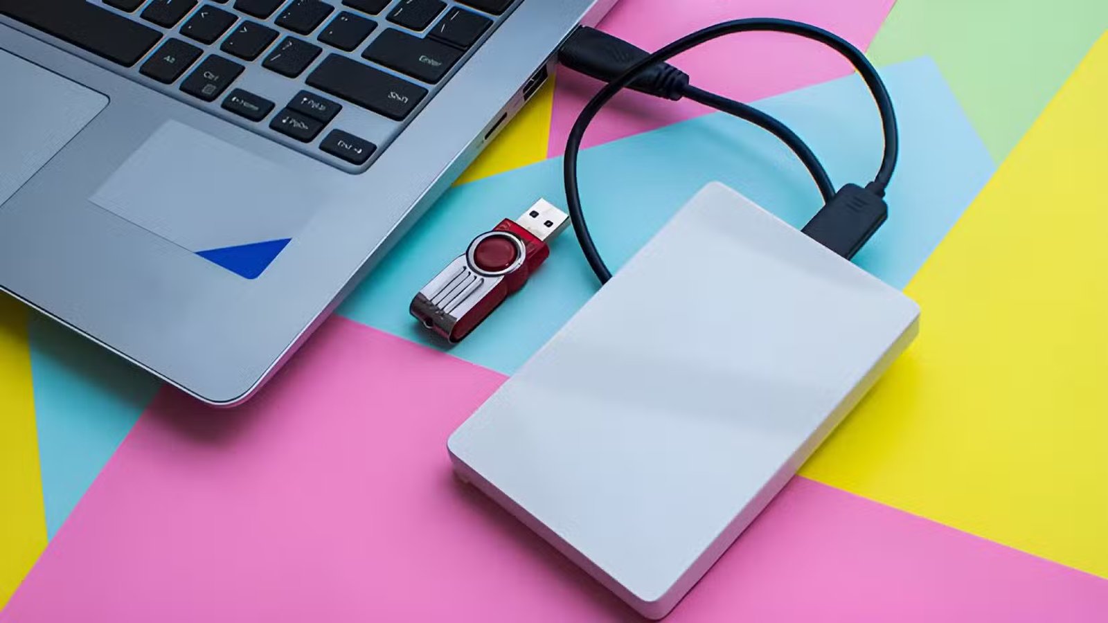 Un disque dur externe connecté à un ordinateur portable à côté d’une clé USB.
