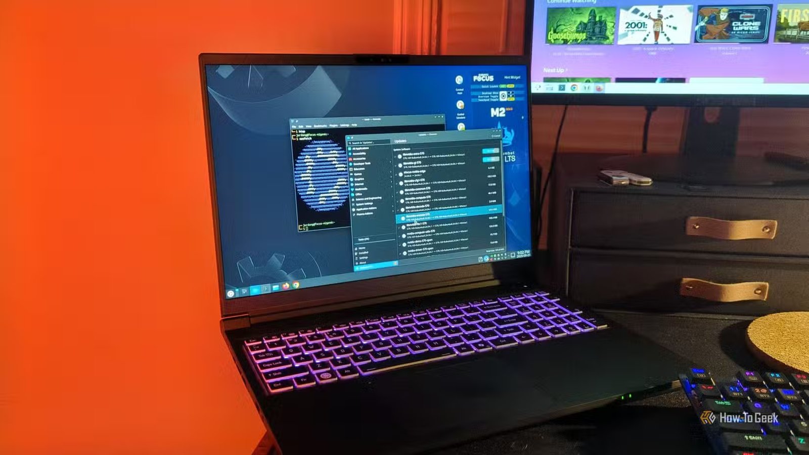 L'ordinateur portable Kubuntu Focus M2 Gen 6 sur un bureau avec un programme de mise à jour du logiciel et un terminal Linux ouvert.