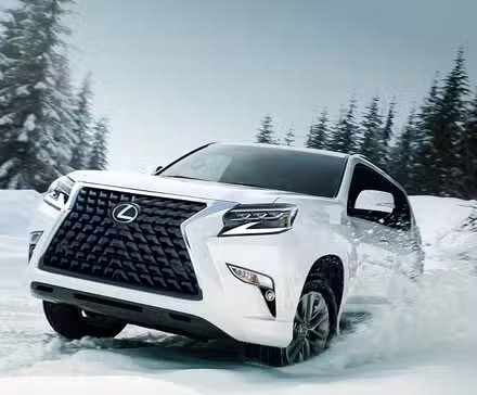 Un Lexus GX 2022 blanc roulant dans la neige dans une zone boisée.
