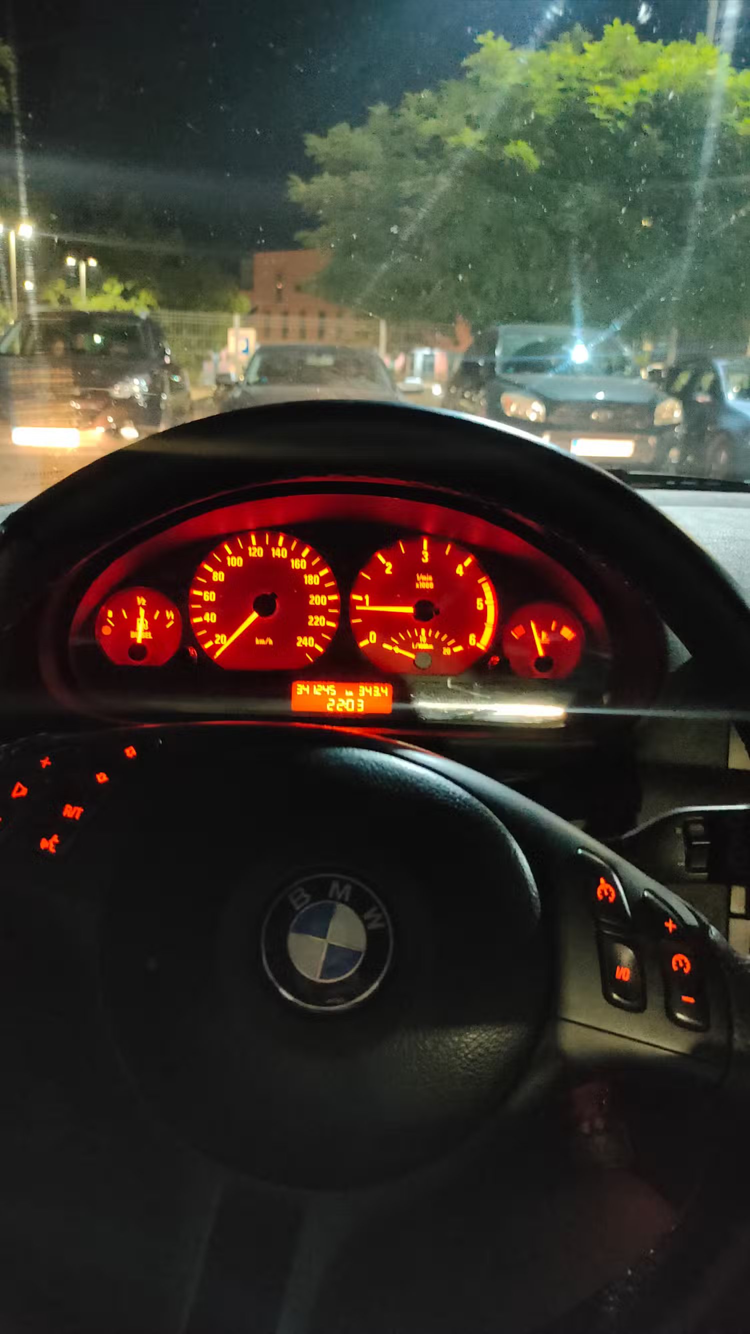 Un volant BMW E46 avec boutons multimédia et groupe d'instruments.