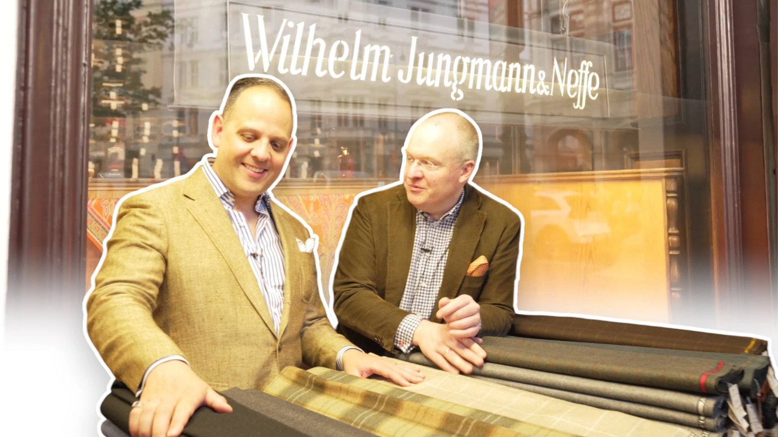 Deux hommes posent avec des tissus devant une enseigne de magasin