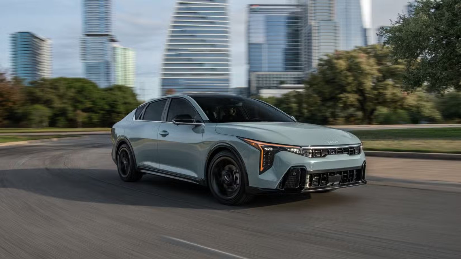 Plan dynamique 3/4 avant d'une Kia K4 2026 grise roulant en ville.