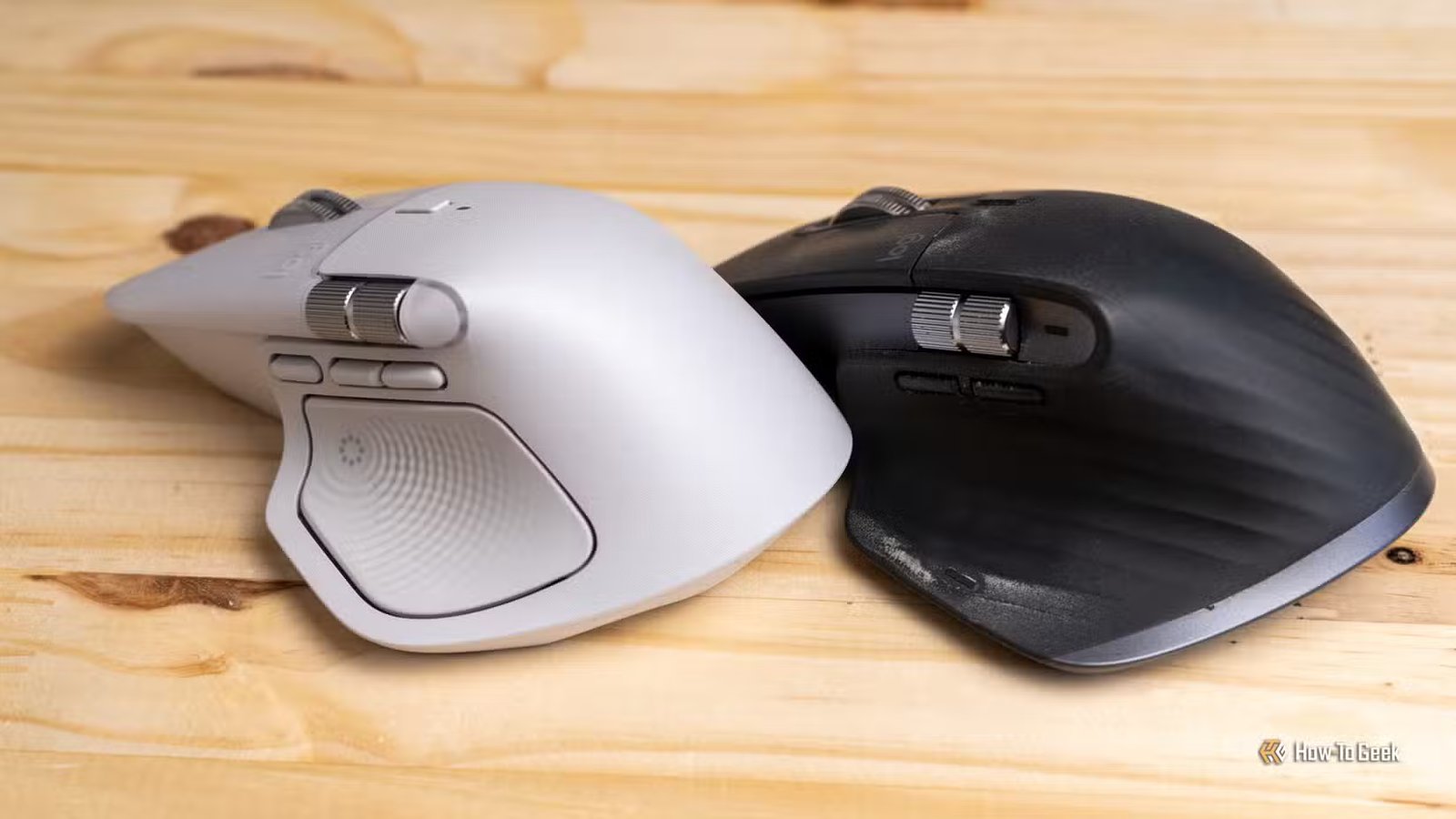 Les Logitech MX Master 4 et MX Master 3S placés face à face sur une surface en bois.