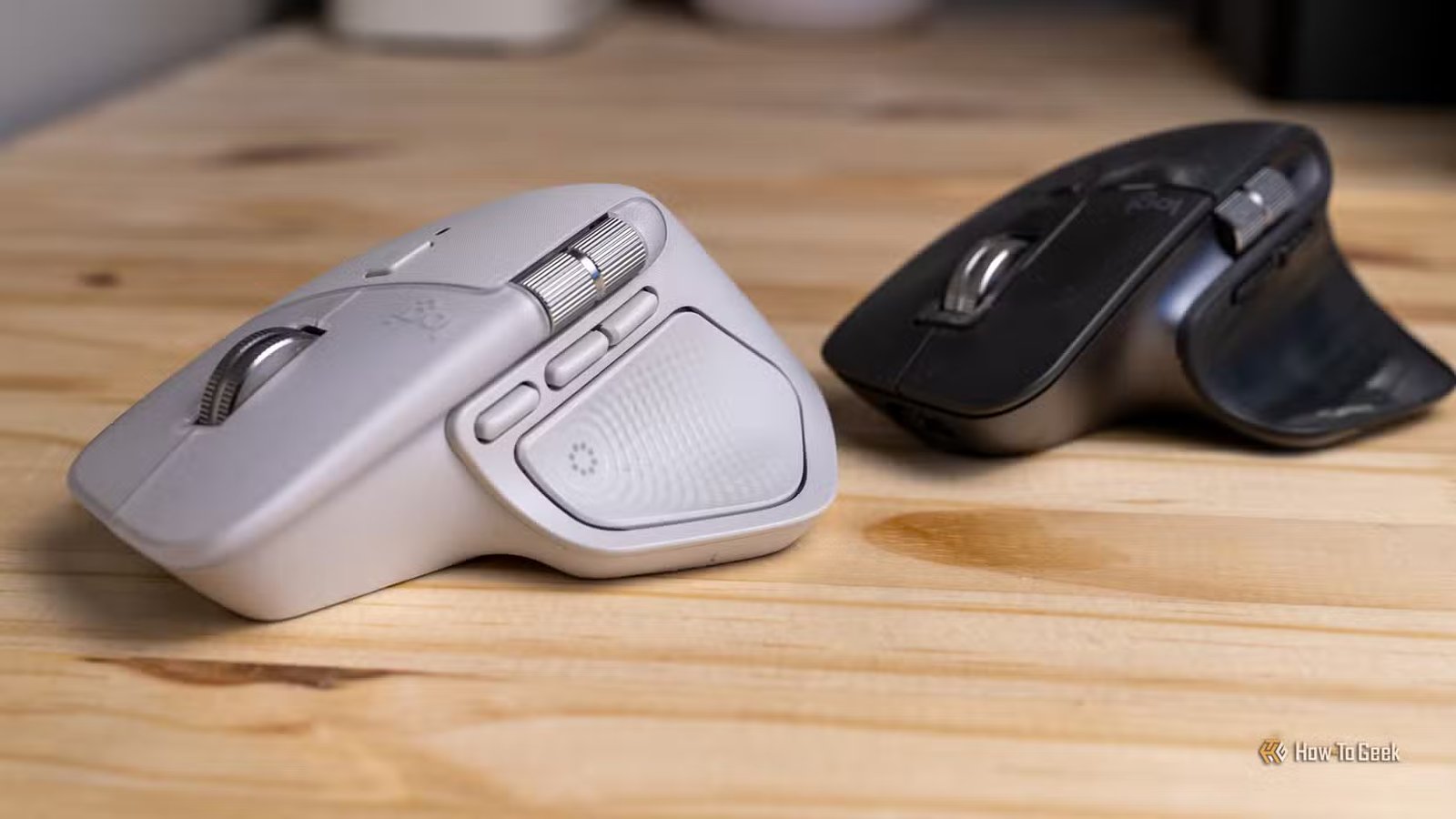 Le Logitech MX Master 4 blanc à côté d'un MX Master 3S noir vu du côté gauche.