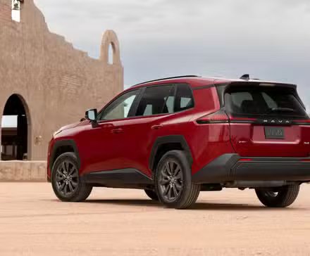 Plan 3/4 arrière statique d'un Toyota RAV4 HEV XLE Premium 2026 rouge.