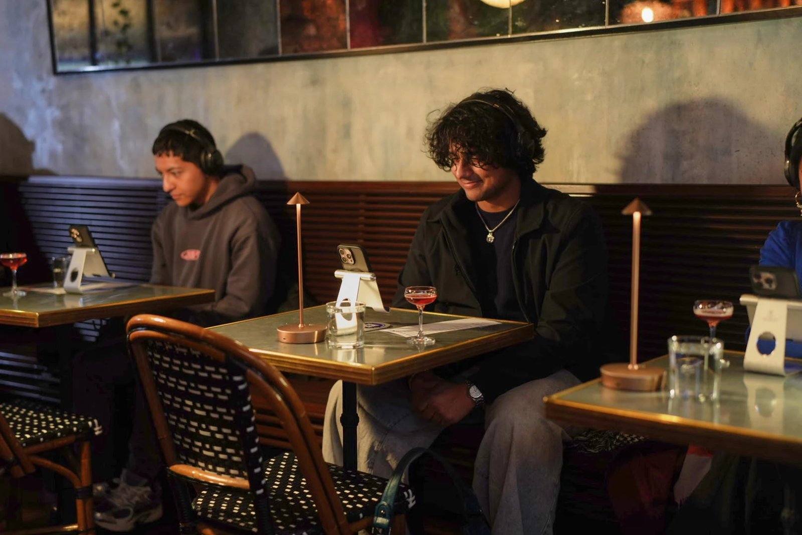 Des gens assis seuls à des tables et regardant des téléphones